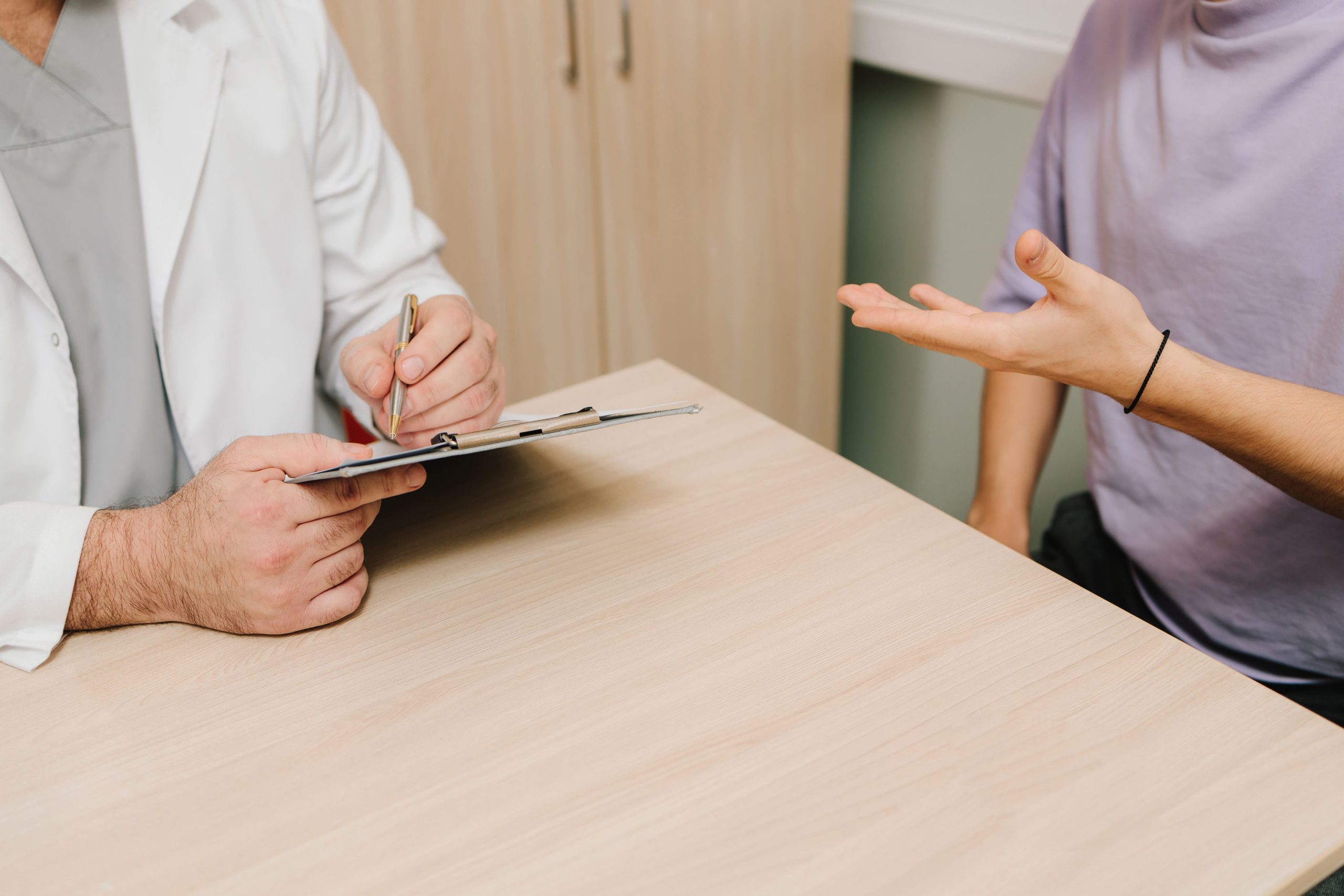 A patient is talking with a doctor in a medical office setting.